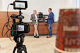 What speaks for us are our employees A video camera films 2 business men drinking coffee